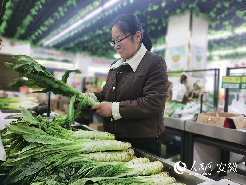 余青青在农贸超市整理蔬菜。人民网 胡雨松摄