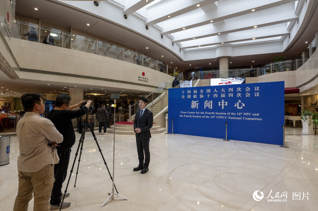 2月27日,媒体记者在全国两会新闻中心采访拍摄。人民网记者 翁奇羽摄